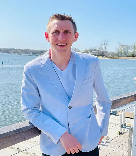 Kohl wearing a light blue blazer by the water